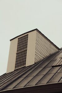 Snow-dusted residential roof showing slate, metal, and asphalt roofing materials with visible flashing and gutters.