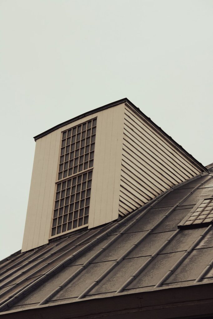 Snow-dusted residential roof showing slate, metal, and asphalt roofing materials with visible flashing and gutters.