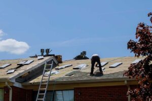 Workers use protective coverings and a secured ladder while renovating a house roof.