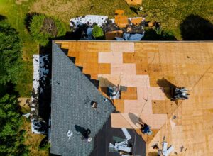 Homeowner viewing roof shingles and gutters from the ground beside a house in early fall.