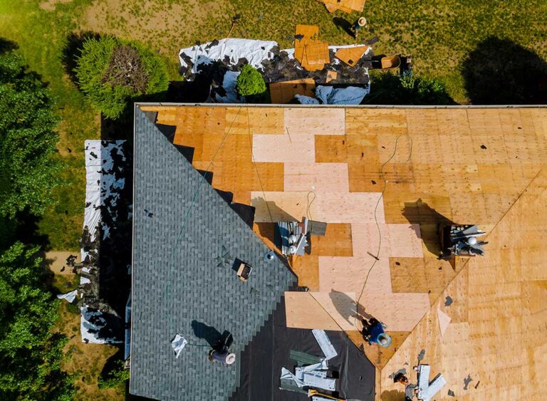 Homeowner viewing roof shingles and gutters from the ground beside a house in early fall.