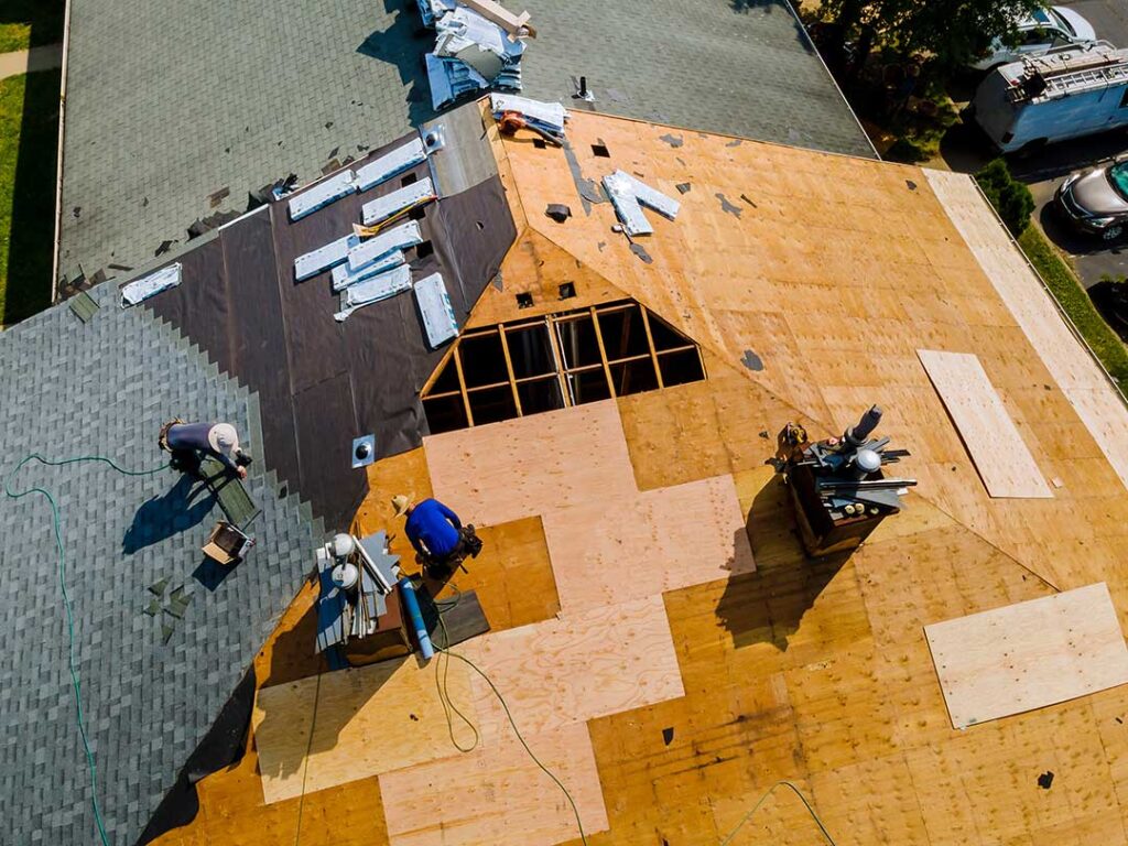 Homeowner inspecting roof shingles with binoculars beside a ladder and gutter-cleaning tools.
