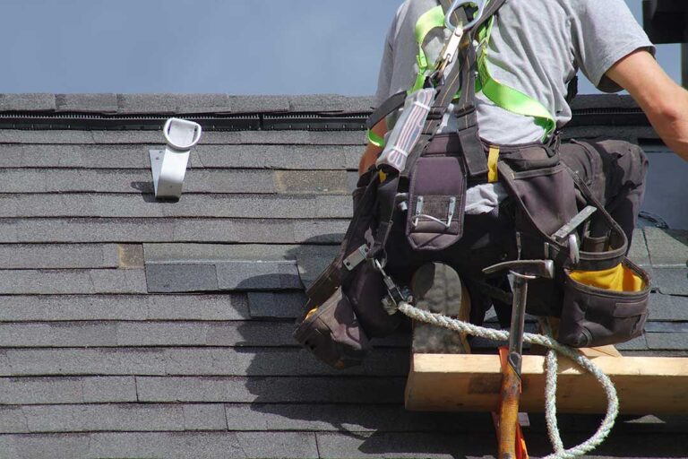 Homeowner photographing damaged shingles and a ceiling water stain while organizing receipts and notes.