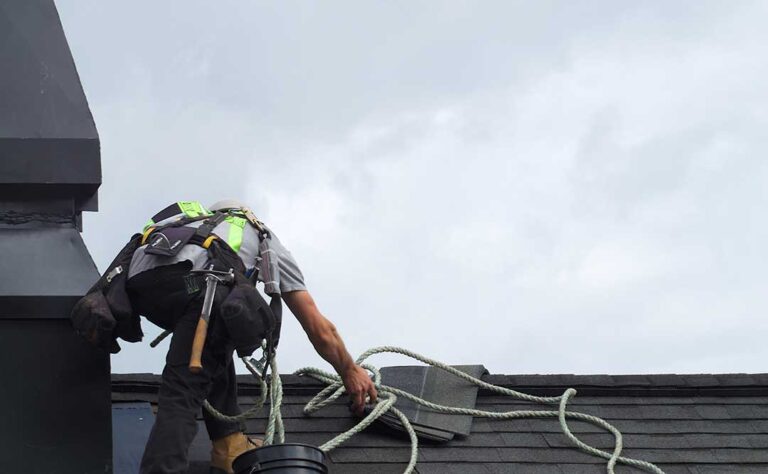 Homeowner placing a bucket beneath a ceiling drip while moving furniture away from the wet area.
